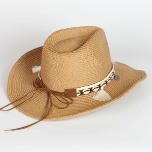 Close-up of woven straw cowboy hat featuring ethnic shell and tassel decorative band