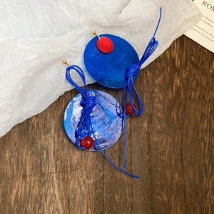 Vue détaillée des boucles d'oreilles bleues artistiques avec perles rouges et corde bleue