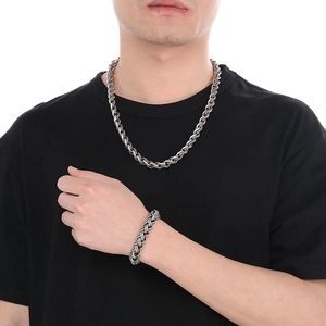 Close-up of a silver stainless steel braided chain necklace and bracelet set on a model