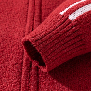 Detailaufnahme der roten Strickjacke mit gerippten Bündchen und feiner Wollstruktur
