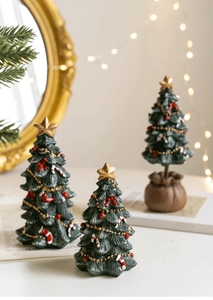 Close-up of mini resin Christmas tree ornaments with star toppers on white surface