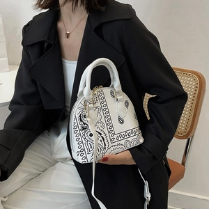 Detail view of shell-shaped white handbag with black paisley print and detachable strap