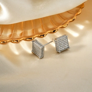 Elegant silver square stud earrings with pave-set cubic zirconia on silk fabric background