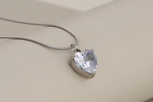 Macro detail of heart-shaped crystal pendant on silver snake chain necklace