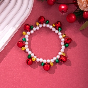Close-up of Christmas bracelet with white pearls and colorful festive metal bells