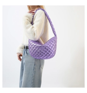 Model carrying a metallic purple quilted crescent shoulder bag with fuzzy white sweater
