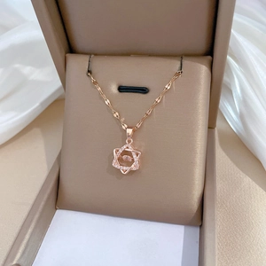 Macro detail of rose gold hexagram necklace with dancing stone in beige jewelry box