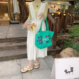French style green floral embroidered canvas tote bag held by a model in outdoor setting