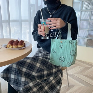 Mint green corduroy tote bag with black smiley face pattern in a lifestyle setting