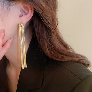 Model wearing gold knot tassel earrings with long fringe for a luxury metallic look