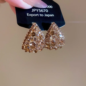 Close-up of gold hollow teardrop earrings with crystals on a black display card