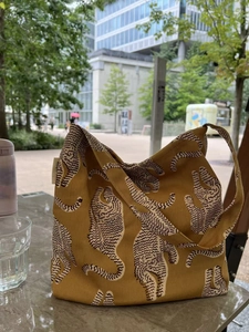 Sac cabas en toile jaune moutarde avec imprimé léopard posé sur une table en marbre