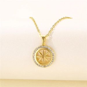 Macro view of gold round medallion necklace with micro-set starburst and clear stones