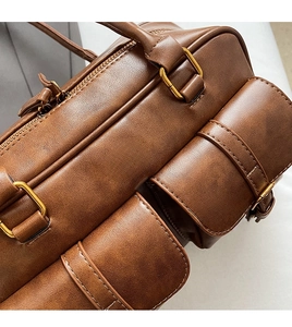 Close-up of vintage brown leather bowling bag featuring gold metal buckles and fine texture