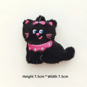 Detail view of a black plush cat brooch with pink bow and embroidered details, 7.5cm size