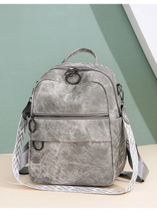 Dettaglio dello zaino in tessuto grigio con tracolla geometrica e cerniere metalliche