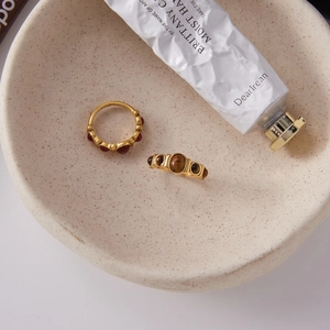 Détail de bagues vintage en acier doré 18K avec pierres oeil de tigre dans un bol