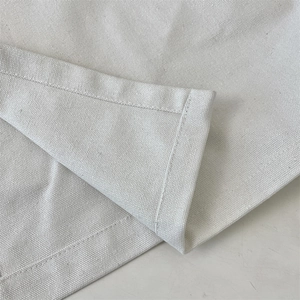 Close-up of white canvas fabric texture with precise double-stitched hem finish