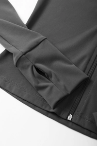 Detailed macro view of athletic jacket sleeve with functional thumbhole and zipper closure