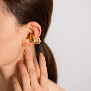 Close-up of a minimalist chunky golden C-shaped ear cuff on a model's ear cartilage
