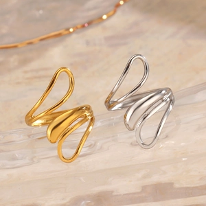 Minimalist gold and silver stainless steel wave rings displayed on a water ripple base