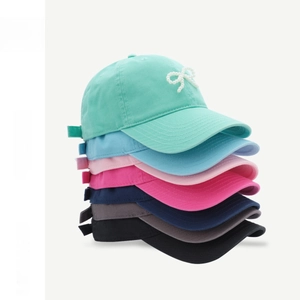 Detailed stack of cotton baseball caps with pearl bow accents in seven vibrant colors