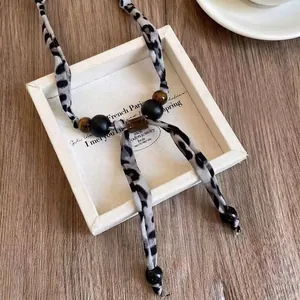 Dettaglio del ciondolo a cuore leopardato e perle in legno su vassoio bianco