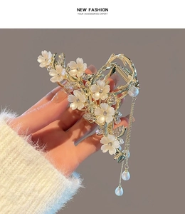 Detail of golden flower hair claw with white petals and long pearl tassel pendant