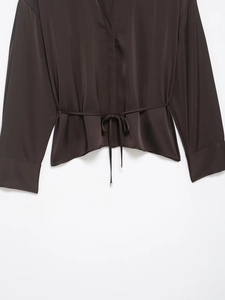 Close-up of a dark brown satin shirt featuring a stylish waist tie and smooth texture