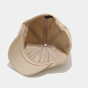 Internal view of khaki cotton newsboy cap showing 6-panel structure and 100% cotton label