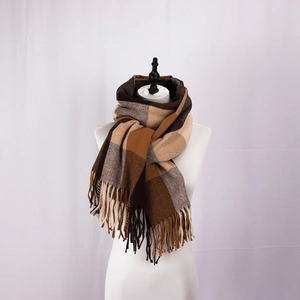 Detail shot of classic earth-tone plaid scarf featuring elegant fringe and soft cashmere texture