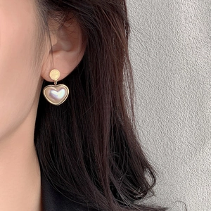 Elegant gold titanium heart earrings with white pearls shown on a female model