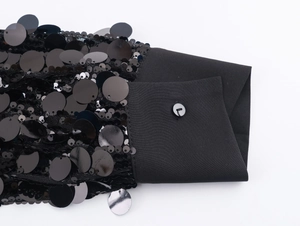 Close-up of black sequined shirt cuff with button detail and shimmering textures
