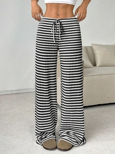 Detail of black and white striped knit trousers featuring a functional drawstring waist