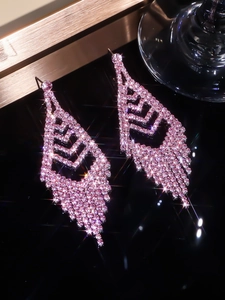 Detailed view of pink crystal tassel earrings with sparkling rhinestones on black surface