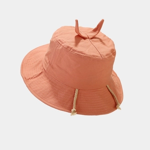 Detail of coral pink cotton bucket hat featuring cute top sprout and woven chin straps