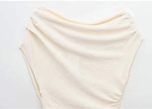 Detail of off-white one-shoulder top showing textured fabric and pleated neckline