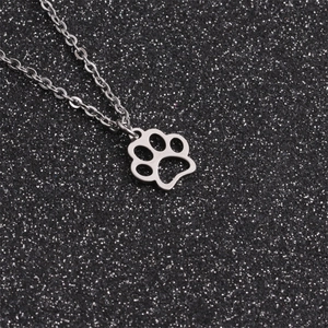 Detailed close-up of a silver paw-shaped pendant with a hollow design on a dark background