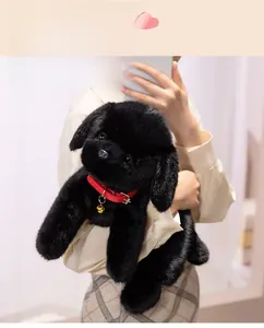 Detail of plush black labrador toy with soft faux fur, red collar, and golden bell charm