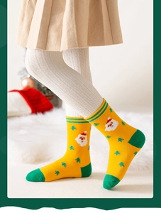 Dettaglio calzini natalizi in cotone giallo con motivi Babbo Natale e albero per bambini