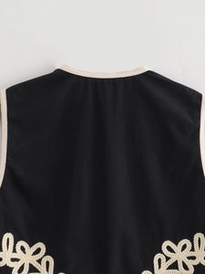 Détail du gilet noir avec bordure contrastée blanche et broderie florale au crochet