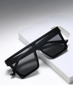 Occhiali da sole quadrati flat top con lenti grigie su una piattaforma geometrica bianca