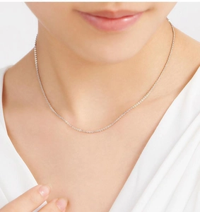 Close-up of a minimalist silver ball chain necklace worn on the collarbone as a stylish accessory