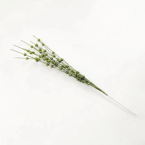 Close-up of artificial green Christmas berries branch with shimmering glitter finish