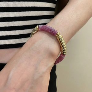 Detailed shot of acrylic beaded bracelet with golden spiral texture beads and purple accents