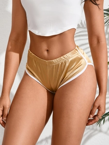 Dettaglio degli shorts sportivi oro metallizzato con bordi bianchi e vita alta