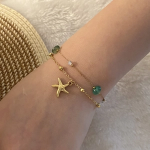 Golden starfish bracelet with green translucent beads on a woman's wrist