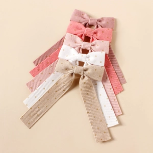 Detailed macro of textured corduroy hair clips with gold polka dots in various pastel colors