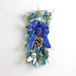 Detail of Christmas wreath featuring a large blue bow, silver ornaments, and snowy pine needles