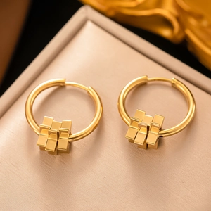 Détail de créoles géométriques dorées avec pendentifs cubes sur un coffret à bijoux chic